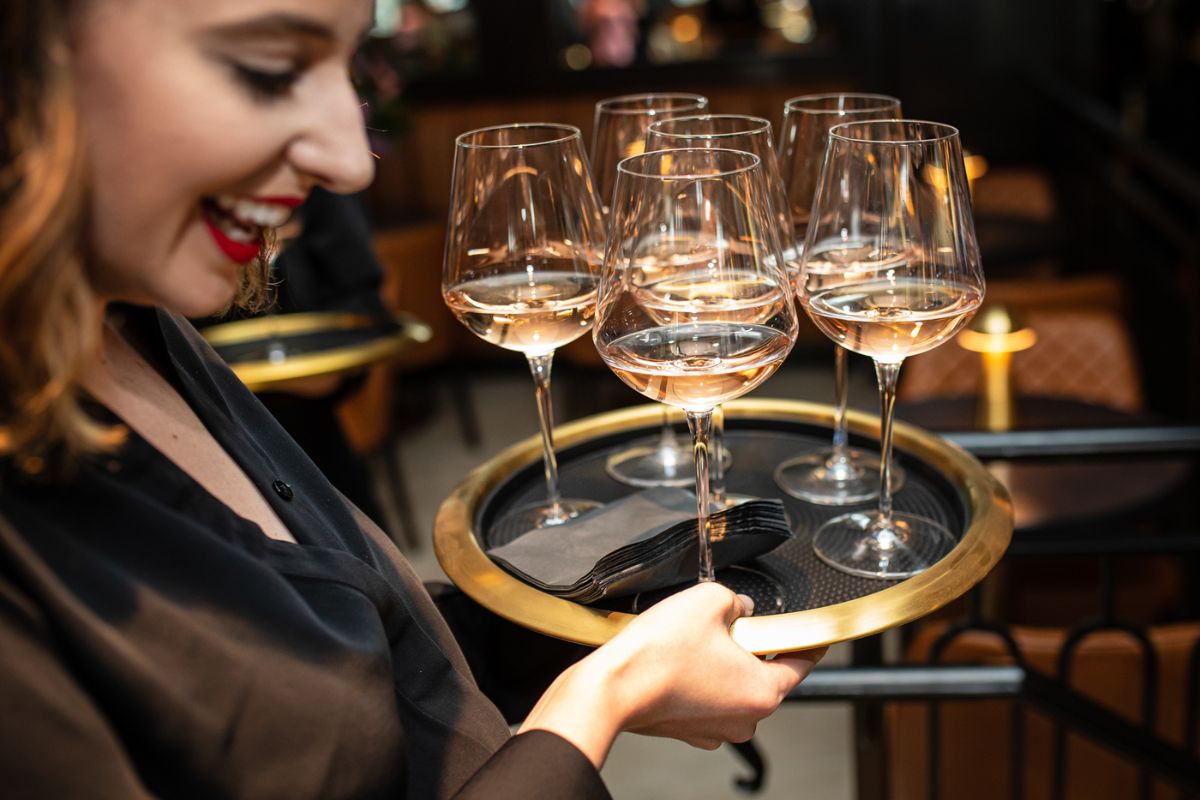 Cocktail server at The Bellevue with a tray of wine glasses serving a holiday party