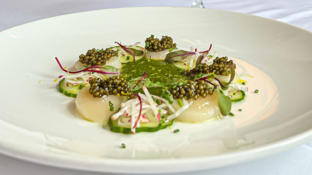 A white plate with Hokkaido scallops, Ostera caviar, aguachile